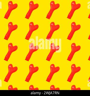 Disposizione piatta di palloncini a forma di cuore rossi gonfiati disposti in righe e posizionati su sfondo giallo in modo chiaro Foto Stock