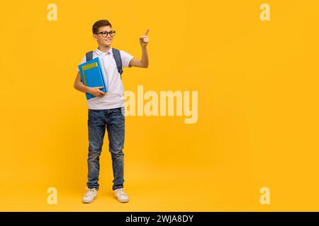 Offerta formativa. Smiling Teen Schoolboy tiene i libri di lavoro e punta da parte Foto Stock