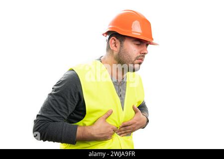 Adulto costruttore uomo in uniforme da lavoro casco di sicurezza e giubbotto fluorescente con indigestione che ha mal di campanella isolato su sfondo bianco studio Foto Stock