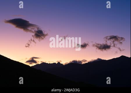 Vivace tavolozza del tramonto: Uno spettacolare cielo dipinto con sfumature multicolori che mostra le silhouette delle Mountain Peaks Foto Stock