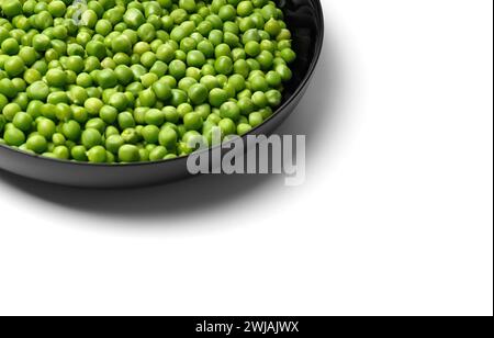 Grani sbucciati di piselli verdi freschi in un piatto nero rotondo su sfondo bianco, spazio di copia. Proteine vegetali, prodotti sani. Foto Stock