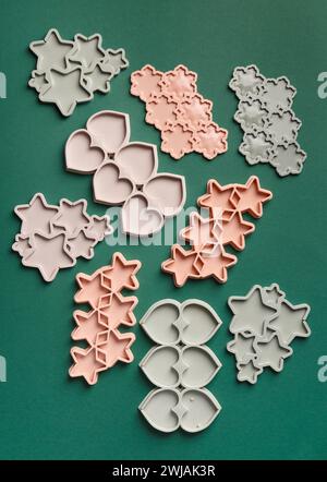 Stampi in silicone sotto forma di fiocchi di neve, cuori e stelle per preparare cioccolato, lecca lecca, dolci su sfondo verde, vista dall'alto. Stampo di caramelle Foto Stock