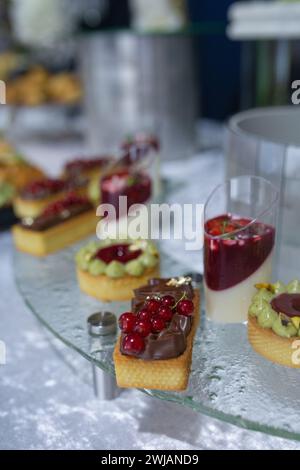 Stuzzichini e dessert colorati e deliziosi su una vetrata durante un evento di catering Foto Stock
