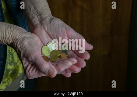 Il pensionato tiene in mano piccole monete in euro, vista ravvicinata - povero pensionato. Foto Stock