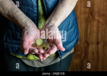 Il pensionato tiene in mano piccole monete in euro, vista ravvicinata - povero pensionato. Foto Stock