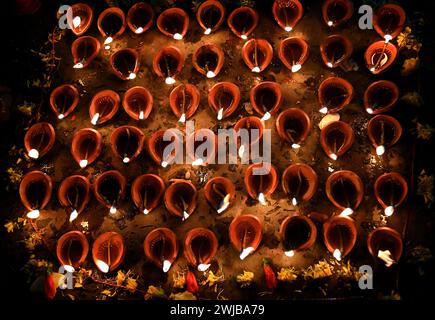 Donne indiane che eseguono un'offerta di preghiera serale con una lampada d'argilla galleggiante sulla riva del fiume Gange a Kolkata, India. Foto Stock
