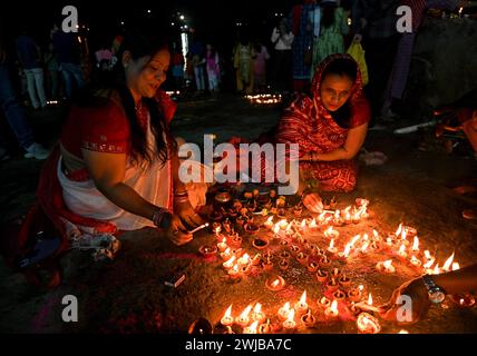 Donne indiane che eseguono un'offerta di preghiera serale con una lampada d'argilla galleggiante sulla riva del fiume Gange a Kolkata, India. Foto Stock