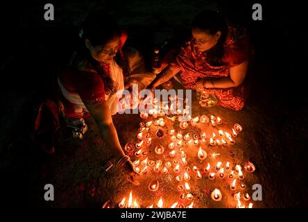 Donne indiane che eseguono un'offerta di preghiera serale con una lampada d'argilla galleggiante sulla riva del fiume Gange a Kolkata, India. Foto Stock