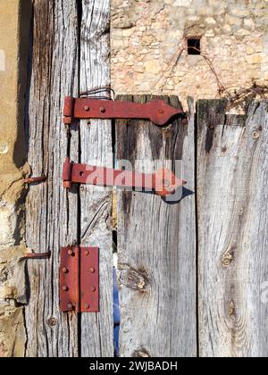 Cerniera arrugginita. Dettaglio di un'antica porta in legno di un villaggio rurale. Foto Stock