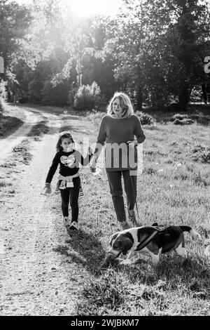 Donna anziana alla moda e la sua bambina godendo una passeggiata in campagna con il loro cane beagle - nonna e nipote felici insieme Foto Stock