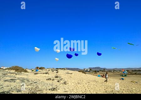 Due uomini e vari piccoli aquiloni blu e bianchi che volano sulle dune di sabbia, Fuerteventura presa nel novembre 2023 Foto Stock