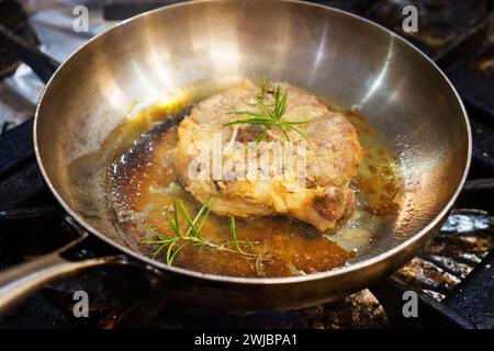 Un pezzo di coscia di agnello viene fritto nell'olio in una padella di ferro. Foto Stock