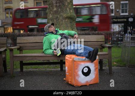 14 febbraio 2024: Un corriere Uber Eats si prende una pausa tra un lavoro e l'altro a Islington Green, Londra. I corrieri Deliveroo e Uber Eats colpiscono stasera tra le cinque e le dieci per garantire condizioni di lavoro migliori e pagare. Foto Stock