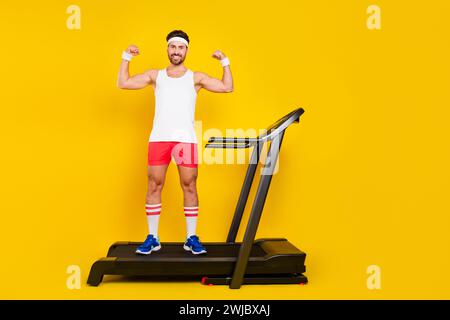 Ritratto completo del corpo di un uomo muscoloso e affascinante, tapis roulant flessibile bicipiti vuoto isolato su sfondo di colore giallo Foto Stock