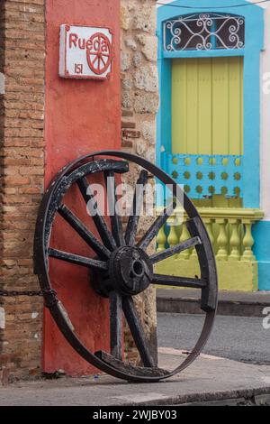 Vecchia ruota del carro. Dettagli architettonici nella vecchia città coloniale di Santo Domingo, Repubblica Dominicana. Un sito patrimonio dell'umanità dell'UNESCO nella Repubblica Dominicana Foto Stock