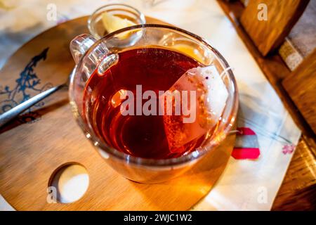Bicchiere di tè rosso all'anca, bustina di tè, limone e miele sul tavolo, primo piano. Foto Stock