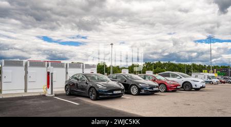 Halmstad, Svezia - 10 luglio 2022: Lunga fila di auto Tesla che si caricano presso il Supercharger Tesla Halmstad. Foto Stock