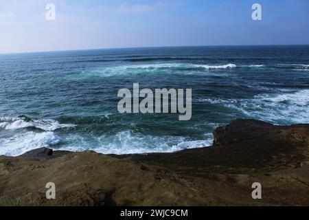Le onde schiumose dell'oceano colpiscono la costa rocciosa con l'orizzonte sullo sfondo Foto Stock
