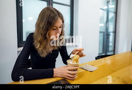 Ragazza che mangia waffle con gelato allo Street food Cafe. Foto Stock