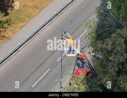 I lavoratori che installano su un sollevatore pneumatico per auto stanno installando una nuova lampada stradale. Foto Stock