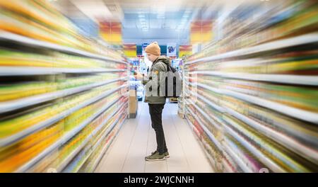 Il cliente sceglie gli articoli alimentari sugli scaffali dei supermercati del negozio di alimentari. Scaffali di mercato con effetto di movimento sfocato. Foto Stock