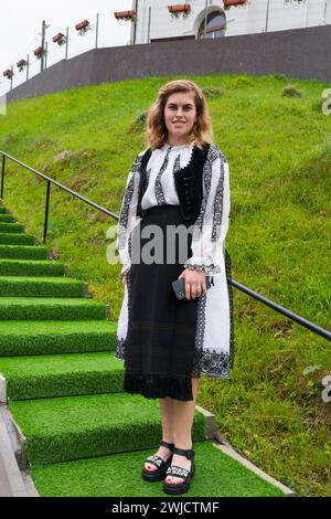 Giovane donna in abito tradizionale in piedi su una scala verde, donna in costume tradizionale, Vadu Motilor, Alba, Transilvania, Romania Foto Stock