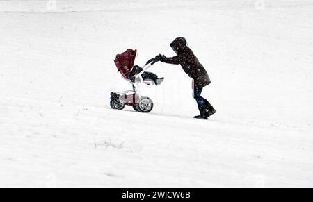 Una donna spinge una carrozza attraverso un parco coperto di neve nel freddo gelido, Berlino, 09/02/2021 Foto Stock