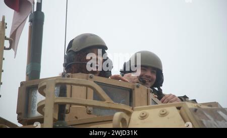 Drawsko Pomorskie, Polonia. 10 febbraio 2024. Washington Commanders cheerleader Bre, fa un giro su un carro armato da battaglia principale M1A2 Abrams dell'esercito americano con la 1st Armored Division presso il Drawsko Combat Training Center, 10 febbraio 2024 a Drawsko Pomorskie, Voivodato della Pomerania Occidentale, Polonia. La National Football League ha collaborato con la Armed Forces Entertainment come parte di Pro Blitz 2024. Credito: SPC. Trevares Johnson/U.S. Army/Alamy Live News Foto Stock