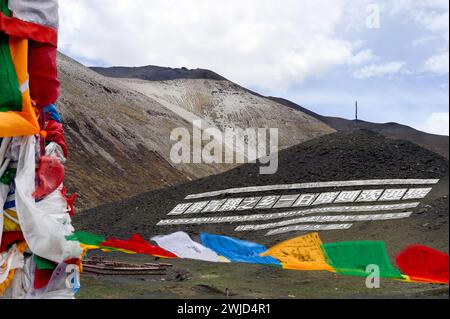 Le bandiere di preghiera tibetane impreziosiscono il segnale di benvenuto alla città di Shigatse, o Xigaze, nella regione autonoma tibetana della Cina. Foto Stock