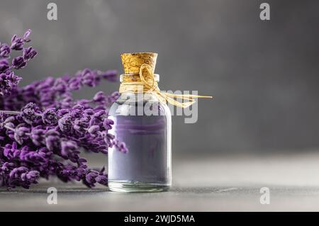 Bottiglia in vetro di olio essenziale di lavanda con fiori e semi secchi di lavanda, massaggio spa con aromaterapia ravvicinata. Oleum di Lavendula Foto Stock