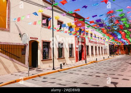 Le bandiere di papel picado di carta decorano la principale via turistica dello shopping di Calle Ezequiel Montes e il Mercado Artesanal nel quartiere storico di Tequisquiapan, Querétaro, Messico. Foto Stock