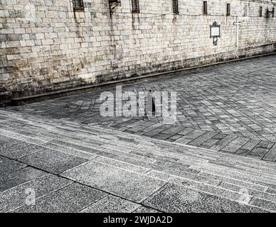 Suora cristiana che cammina attraverso Praza da Quintana nella città vecchia di Santiago de Compostela. Il quadrato è diviso in due livelli diversi. Foto Stock