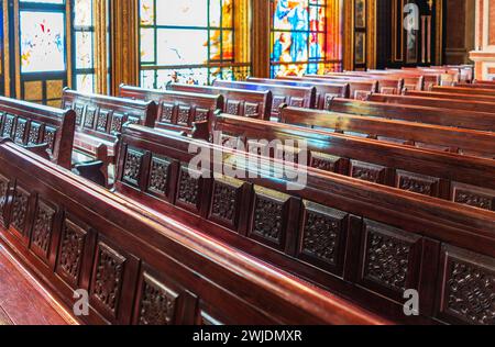 Panchine vuote in legno di una chiesa cristiana. Alterazione sfocata sullo sfondo. Messa a fuoco selettiva. Concetto di servizio religioso o chiese vuote. Righe Foto Stock