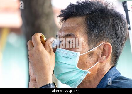 AYUTTHAYA, THAILANDIA, 10 dicembre 2023, Un uomo con una lente d'ingrandimento esamina i gioielli per strada Foto Stock