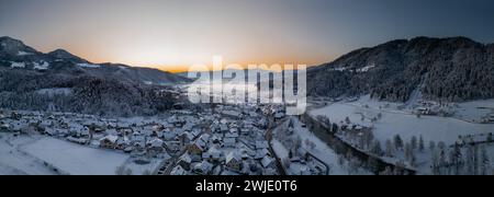 Splendido villaggio di Ljubno ob Savinji, sede di gare femminili di salto con gli sci. Panorama invernale dall'alto del villaggio la mattina presto. Il sole sorge sopra Foto Stock