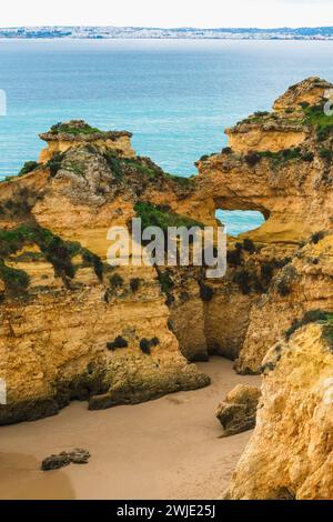 La costa frastagliata con grotte, onde oceaniche che si infrangono e una spiaggia sabbiosa crea un affascinante paesaggio costiero Foto Stock