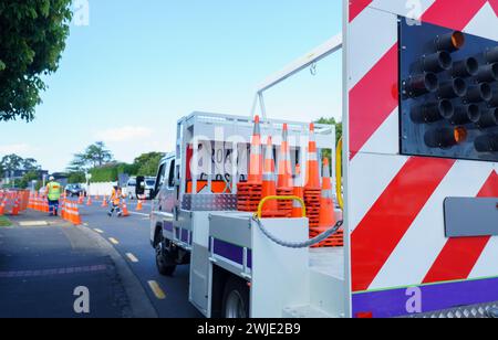 Autocarro carico con segnaletica stradale chiusa e coni stradali arancioni. I lavoratori irriconoscibili mettono i coni stradali sulla strada. Lavori stradali ad Auckland. Foto Stock