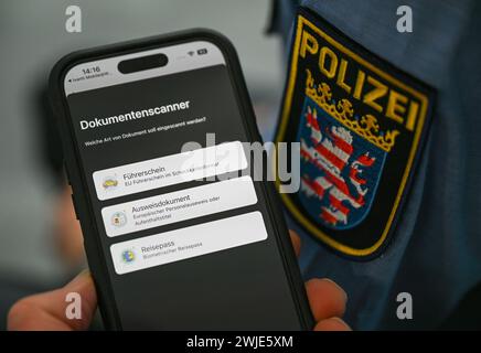 PRODUZIONE - 8 febbraio 2024, Assia, Francoforte sul meno: Un'app che funge da scanner di documenti per patenti di guida, carte d'identità o passaporti viene presentata sul cellulare di un agente di polizia nell'Innovation Hub 110 della polizia dell'Assia. Incidenti stradali o furti: Gli agenti di polizia sono in grado di elaborare un numero sempre maggiore di casi sui loro cellulari. Foto: Arne Dedert/dpa Foto Stock