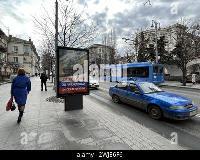 14 febbraio 2024, Ucraina, Sewastopol: In vista delle elezioni presidenziali russe del 17 marzo, ci sono manifesti in molti luoghi della città che promuovono la rielezione del leader del Cremlino Putin. Il poster nel centro della città portuale recita "per la Russia". Per il presidente. Per Sevastopol'. Molti Crimea sono grati a Putin per aver conquistato la penisola dall'Ucraina con la forza dieci anni fa e per averla integrata nel gigantesco impero. Quest'anno la Russia festeggia il decimo anniversario dell'annessione della Crimea, che fa parte dell'Ucraina ai sensi del diritto internazionale. Foto: Ulf Mauder/dpa Foto Stock