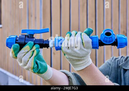 Il raccordo di compressione della valvola in PP viene utilizzato durante l'installazione dell'alimentazione dell'acqua esterna per l'acqua potabile fredda e l'irrigazione, l'idraulico stringe il dado di fissaggio. Foto Stock