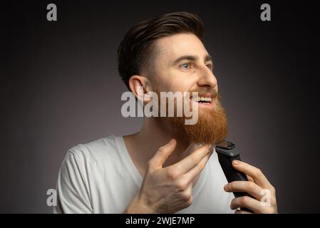 L'uomo taglia la barba con un rifinitore Foto Stock