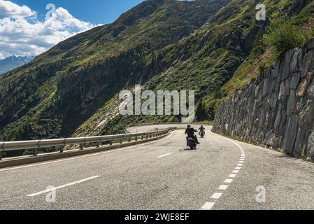 Due ciclisti che viaggiano sulla tortuosa strada del passo di Grimsel, Obergoms, Canton Vallese, Svizzera Foto Stock