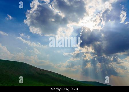 Fasci di sole che si infrangono tra le spettacolari nuvole di cumulus. Il tempo cambia da tempesta a soleggiata. Concetto di speranza o religione. Foto Stock