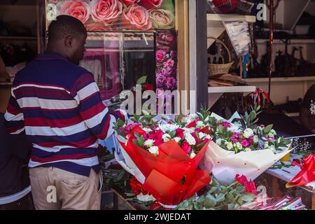 Nairobi, Kenya. 14 febbraio 2024. Un fiorista keniota confeziona fiori al suo chiosco al mercato cittadino di Nairobi durante il giorno di San Valentino a Nairobi. I kenioti riempivano varie strade in tutto il paese mentre celebravano San Valentino nonostante la dura situazione economica che si sta attualmente vivendo. Anche i fioristi e i negozi di articoli da regalo sparsi in tutta la città di Nairobi hanno registrato un aumento del traffico, mentre i kenioti colsero il momento di acquistare regali e cestini per i loro cari. Il Kenya è un grande esportatore di fiori in Europa e in Medio Oriente. Credito: SOPA Images Limited/Alamy Live News Foto Stock