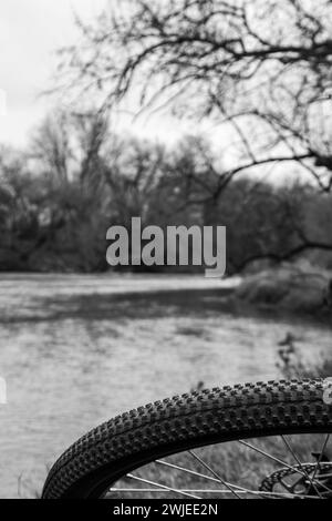 Una fotografia monocromatica con una bicicletta appoggiata sul bordo di un fiume Foto Stock