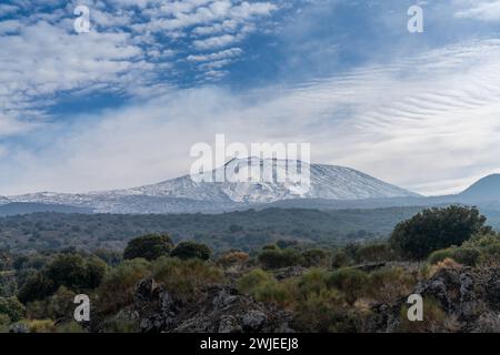 Una vista sull'Etna innevato e sulle colline selvagge della campagna siciliana Foto Stock