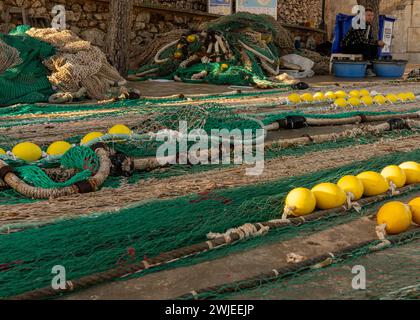 Puerto de Cala Figuera, Spagna - 22 gennaio 2024: Pescatore di Maiorca che ripara le reti e ripara le lenze di pesca nel porto di Cala Figuera a Mallor Foto Stock