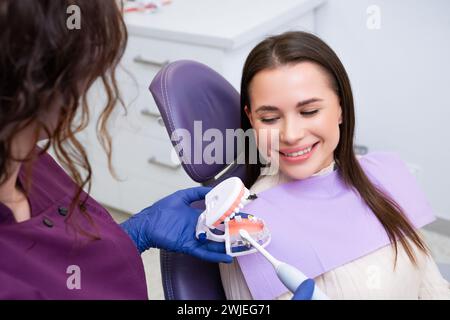 Il dentista spiega a fondo la tecnica corretta per lo spazzolino dei denti da donna. L'esperto dentale sottolinea l'importanza di mantenere l'igiene orale Foto Stock
