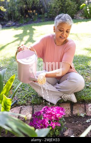 Una donna birazziale matura tende a giardinare le piante Foto Stock