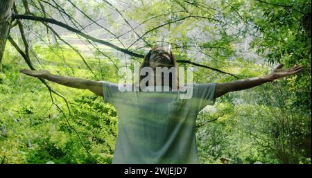 Donna con le braccia spalancate in una foresta Foto Stock